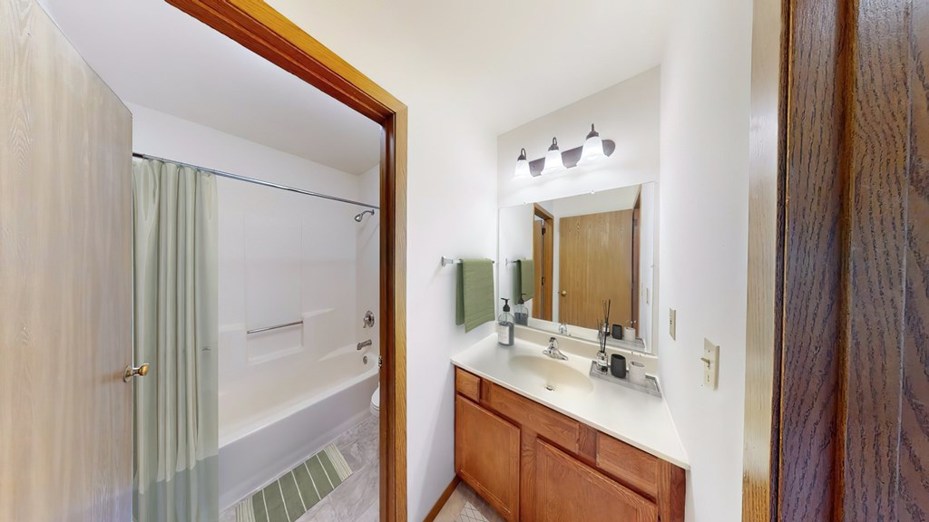 A bathroom with a sink, mirror, and shower.
