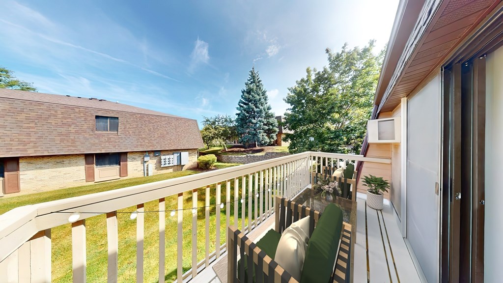 A balcony with a white railing and a green cushioned chair.