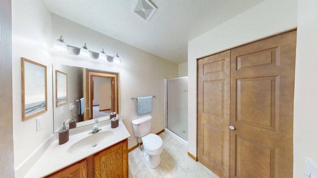 A bathroom with a toilet, sink, mirrors and a wooden door.