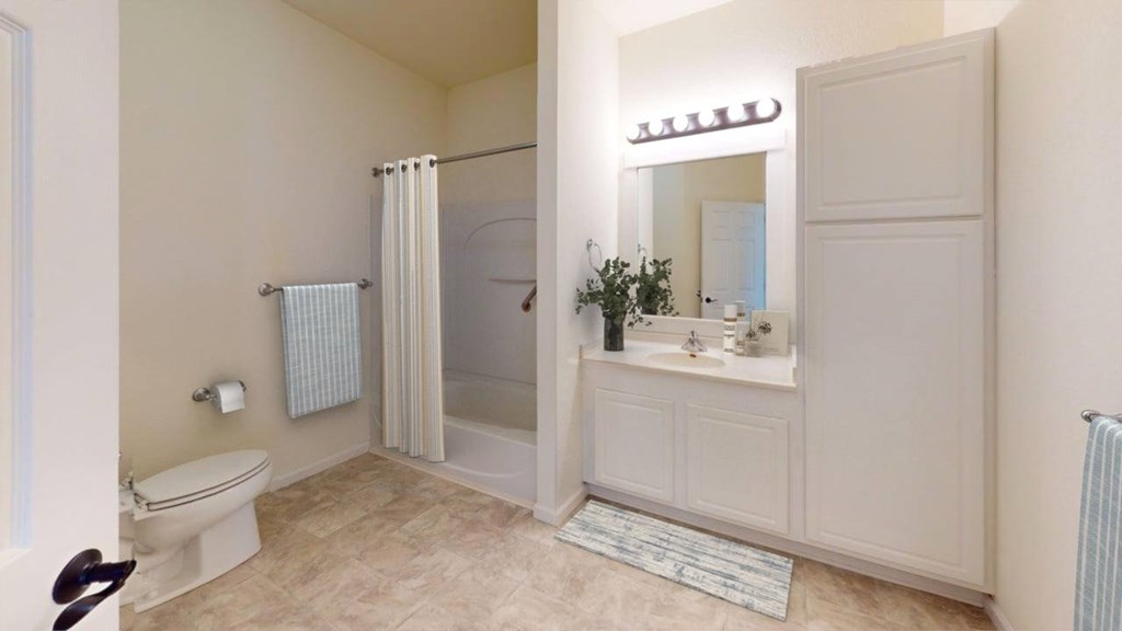 A bathroom with a toilet, sink, and shower.