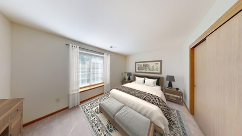 A bedroom with a large bed and a window with curtains.
