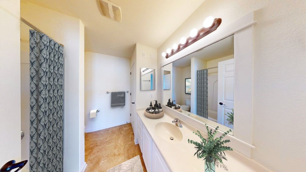 A bathroom with a white counter and a large mirror.