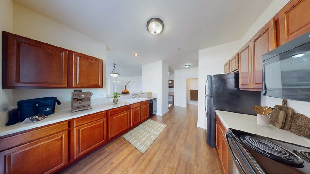 A kitchen with wooden cabinets and a black fridge.