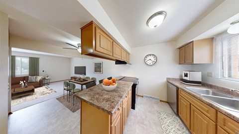 A kitchen with a brown counter top and a clock on the wall.