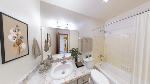 A bathroom with a white tub, sink, and toilet.