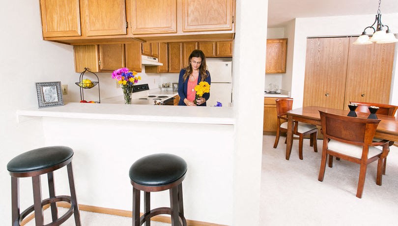 a woman standing in a kitchen looking into a mirror