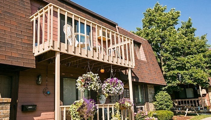 a house with a balcony with chairs and flowers on it