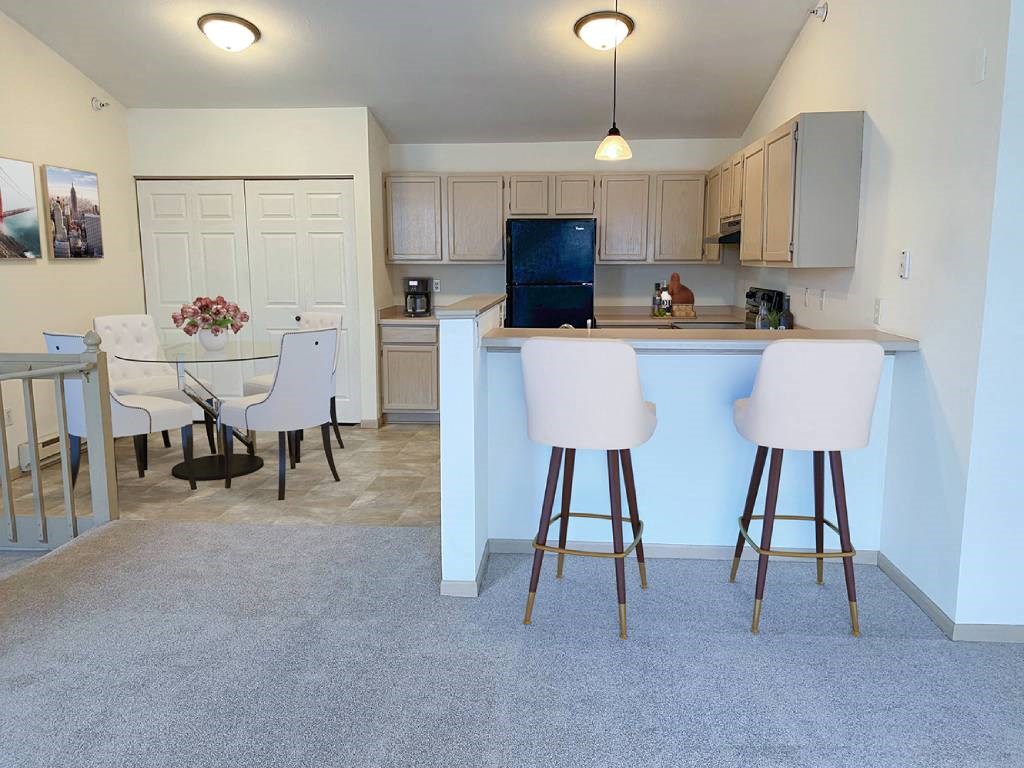 a kitchen and dining area with a bar and chairs
