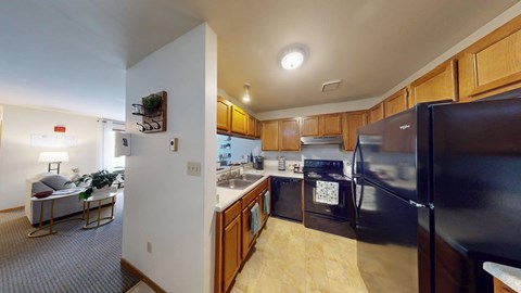 A kitchen with a black refrigerator and wooden cabinets.