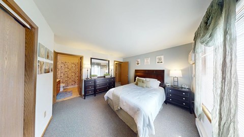A bedroom with a large bed and a window with curtains.