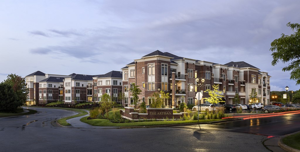 a large apartment building on a street corner at dusk