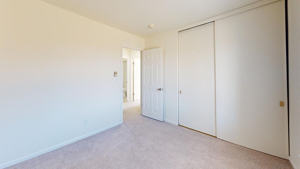 a bedroom with white walls and a door to a closet