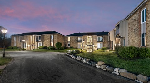 a row of brick apartment buildings with green grass and a road