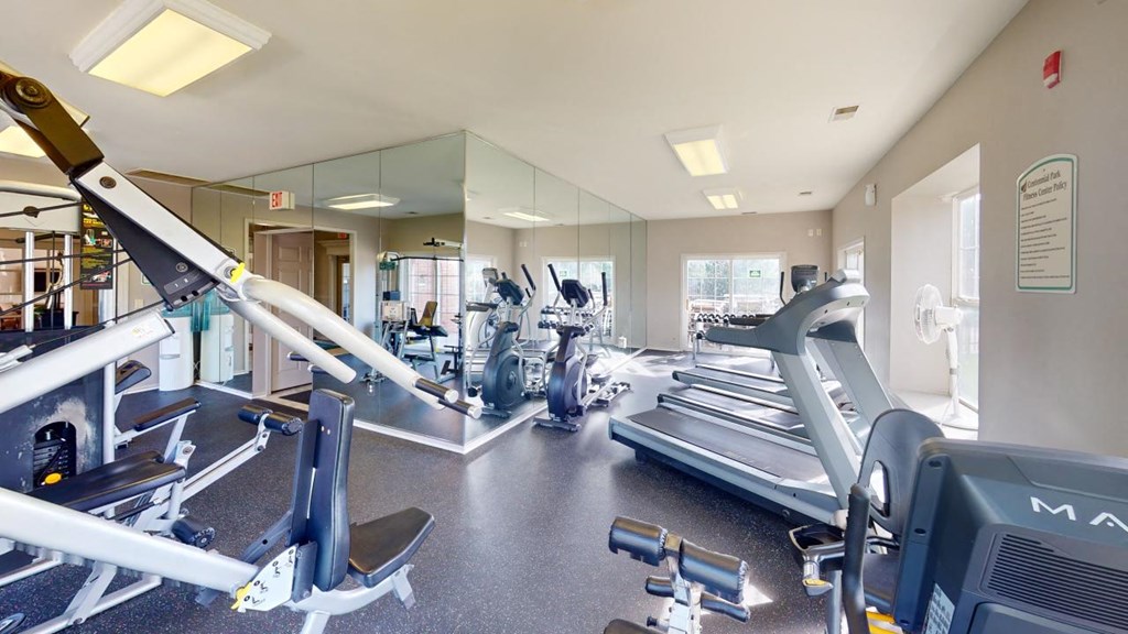 a gym with cardio equipment and mirrors in a building