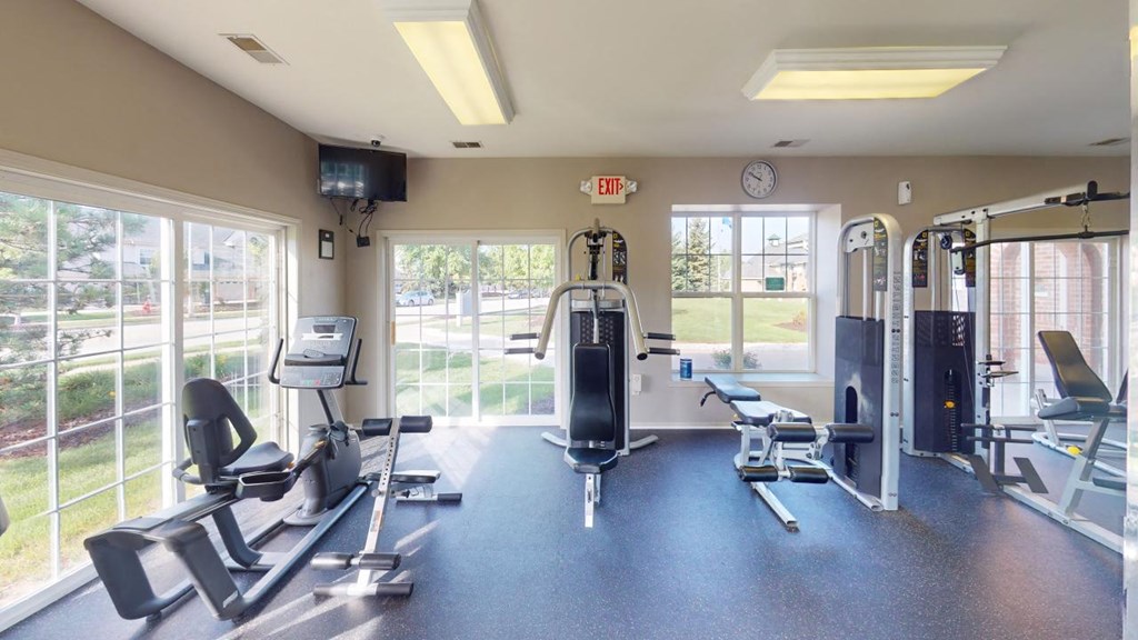 a gym with weights and cardio equipment and windows