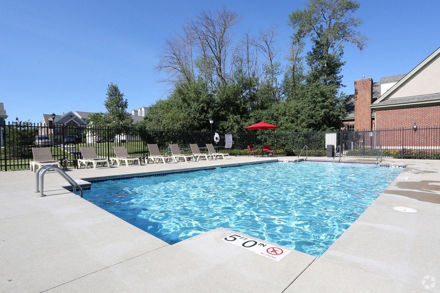 a swimming pool with chairs around it in front of a building