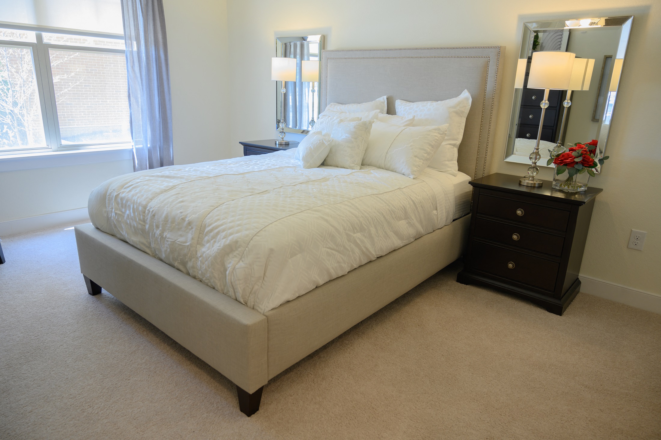 a bedroom with a bed and two nightstands and a window