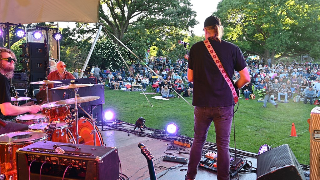 A man with a guitar is performing on stage at a concert.
