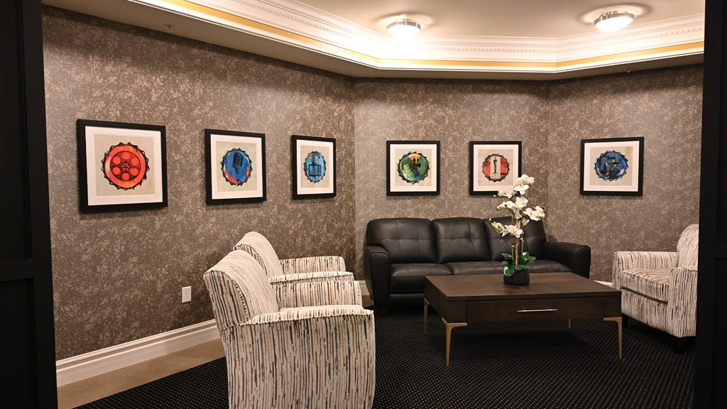 a living room with leather couches and chairs and paintings on the wall