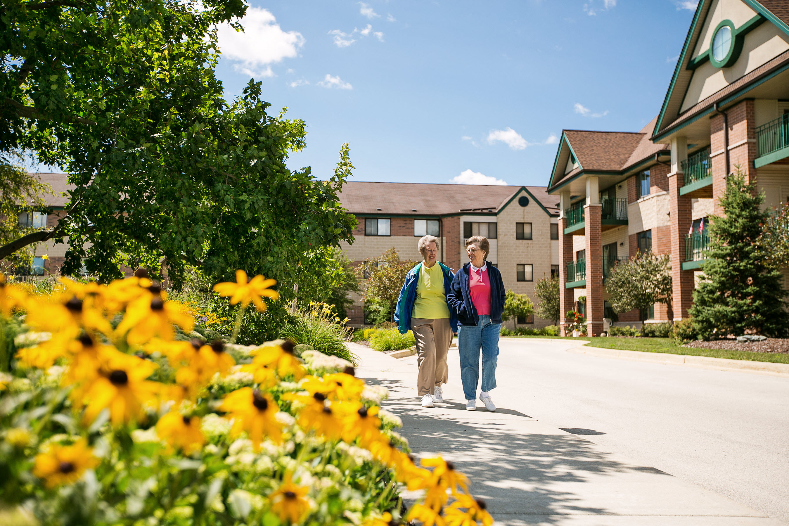 a couple walking down a sidewalk in front of an apartment building