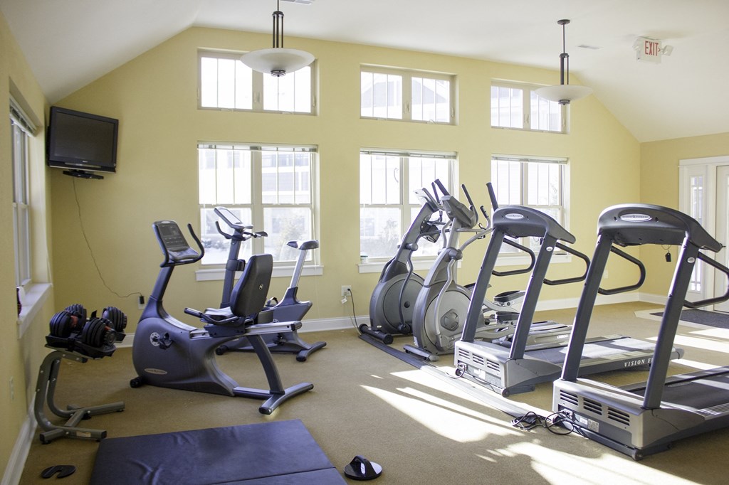 a gym with several exercise bikes and a tv