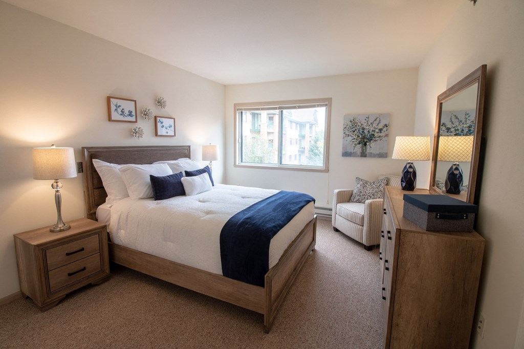 a bedroom with a bed and a chair and a window