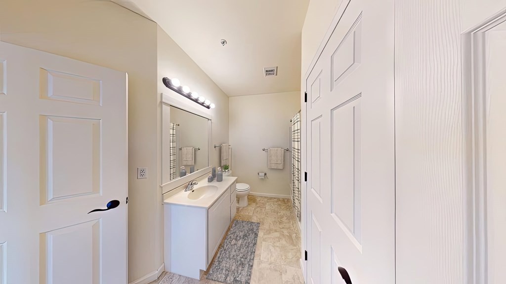 A white bathroom with a sink, mirror, and toilet.