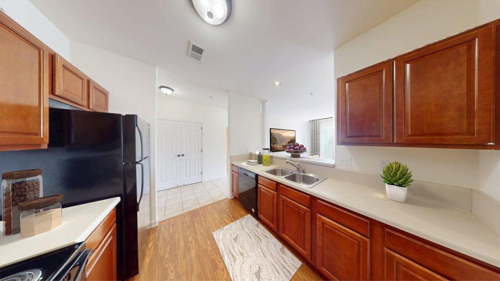 A kitchen with wooden cabinets and a black refrigerator.