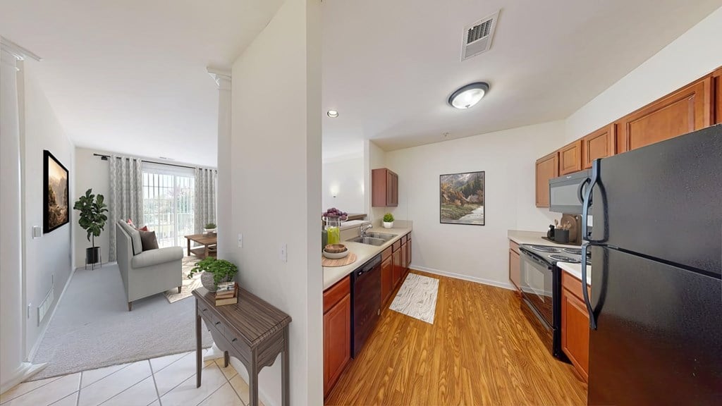 A kitchen with wooden floors and a black refrigerator.