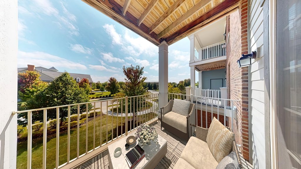 A balcony with a table and chairs overlooking a garden.