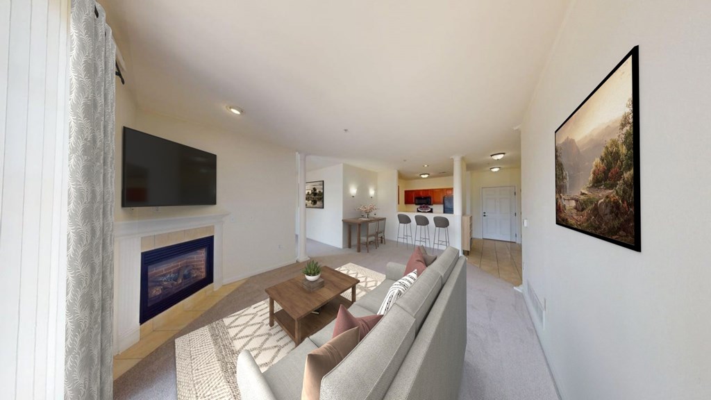 A living room with a grey couch and a flat screen TV mounted on the wall.