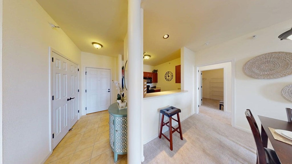 A hallway with a blue cabinet and a wooden stool.