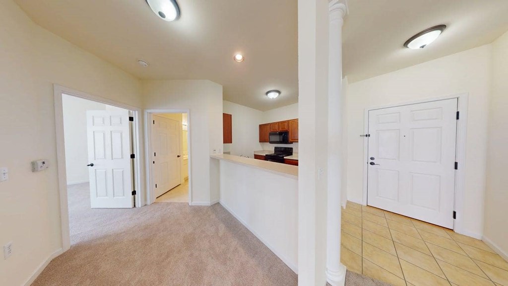 A spacious room with white walls and a carpeted floor.