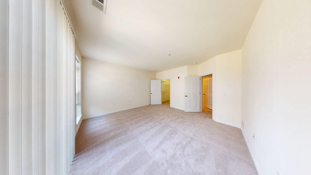 A room with a carpeted floor and two doors.