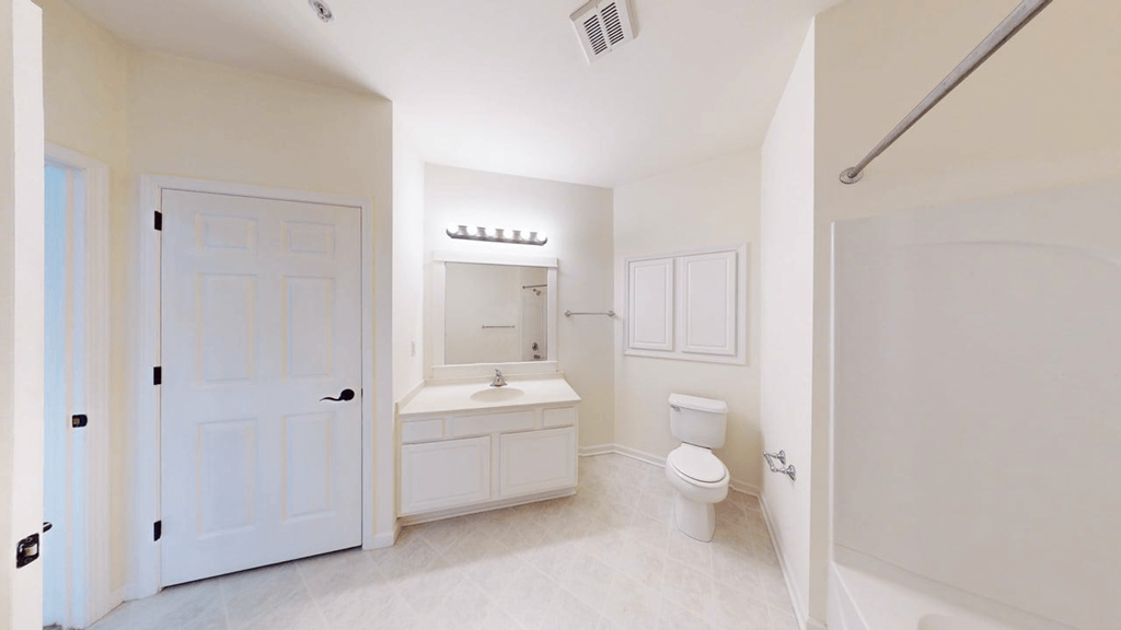 A white bathroom with a toilet, sink, and mirror.