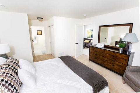 A bedroom with a large bed and a wooden dresser.