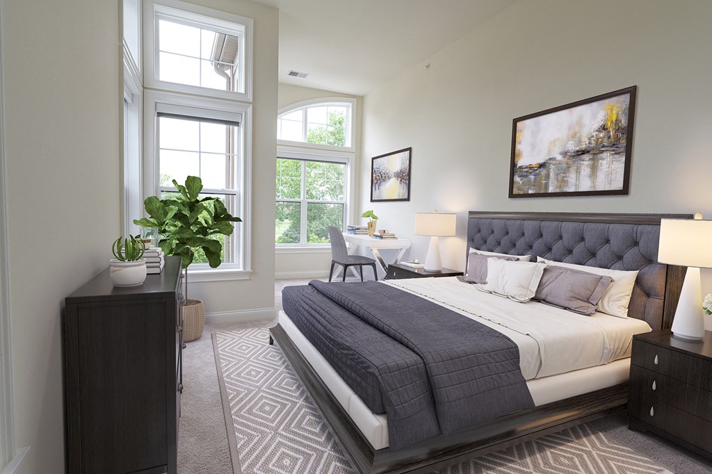 a bedroom with a bed and a table and two windows