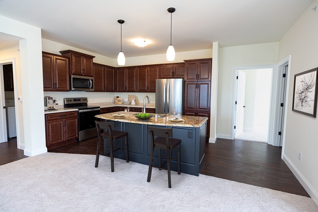 a kitchen with a large island and a stainless steel refrigerator