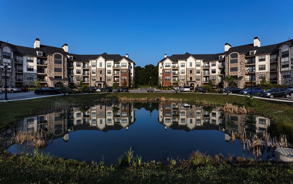a reflection of an apartment building in a pond