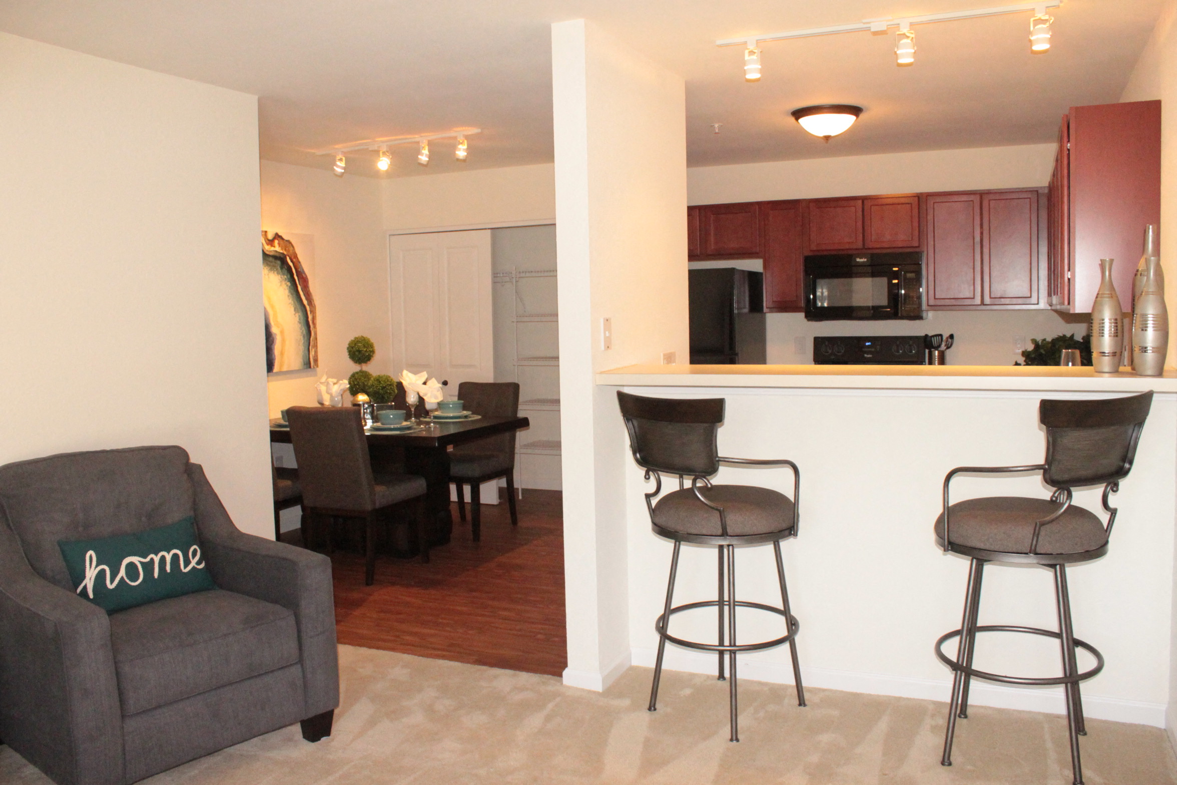 a view of a living room and a kitchen with a bar and chairs