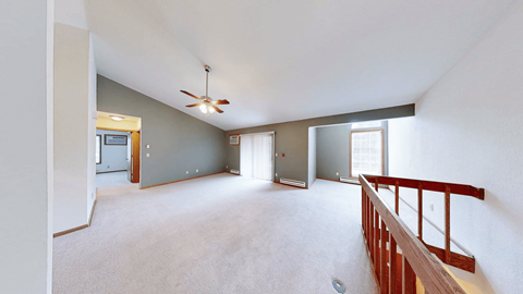 A spacious room with a ceiling fan and a balcony.