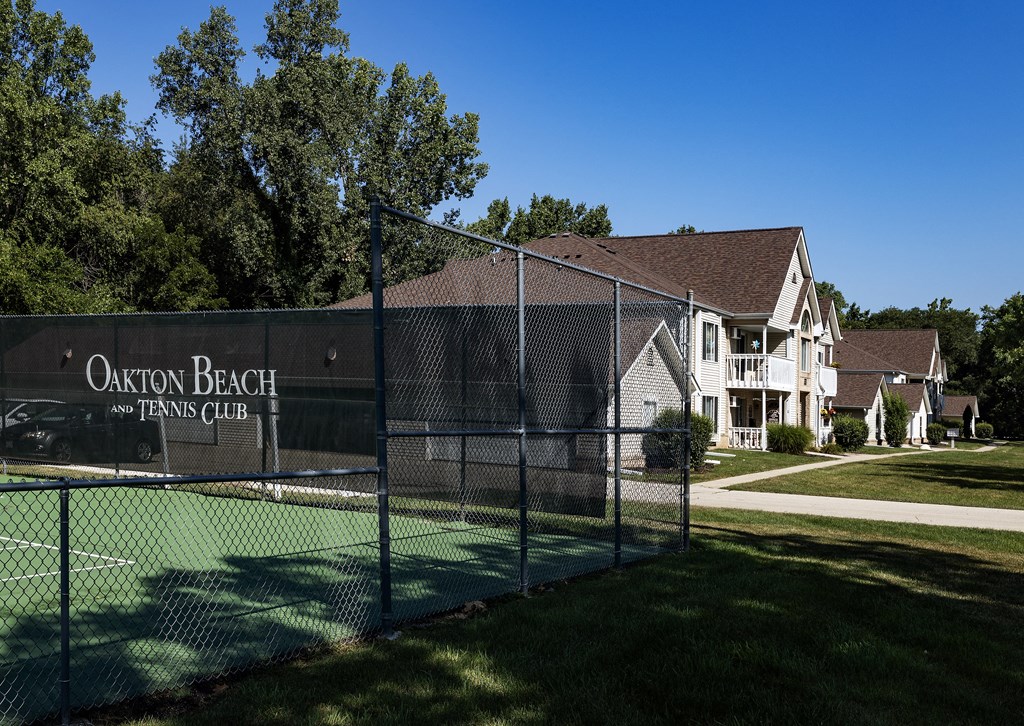 a fence with a tennis court in front of a house