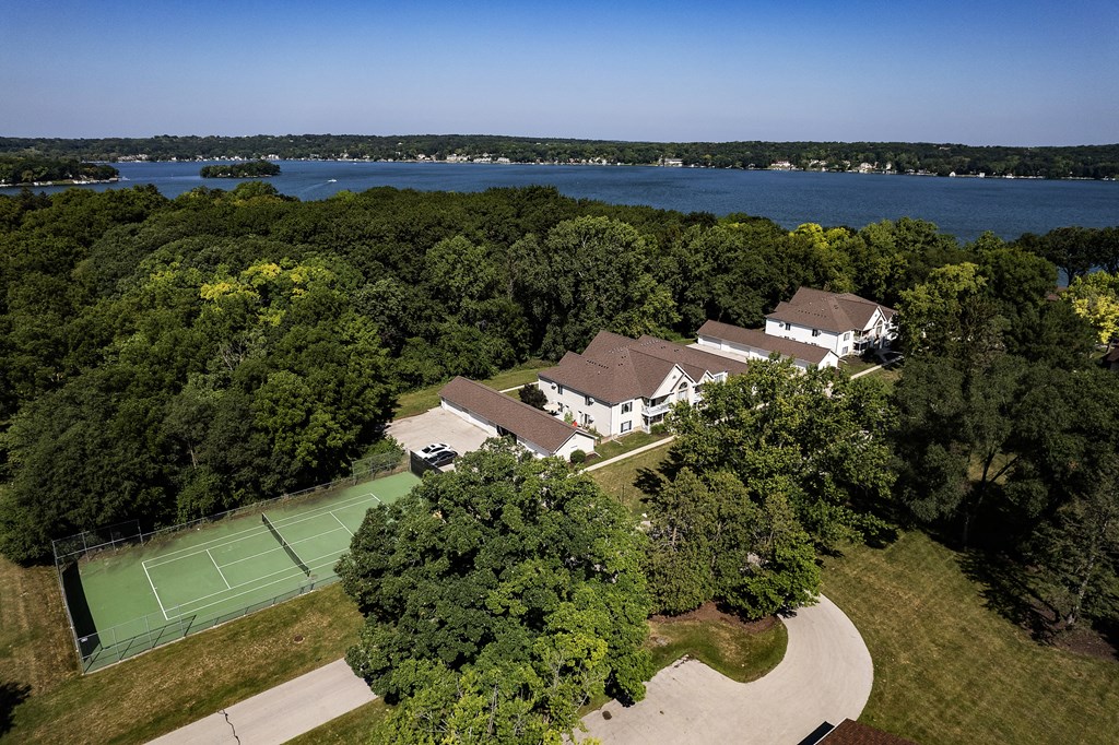 a mansion with a tennis court and a lake in the background