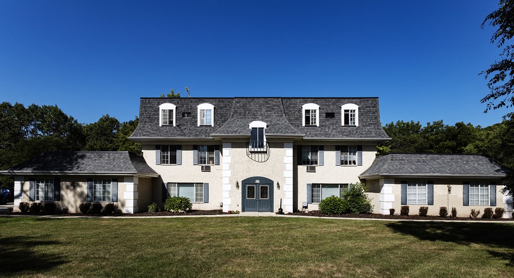 a large white house with a gray roof and a lawn