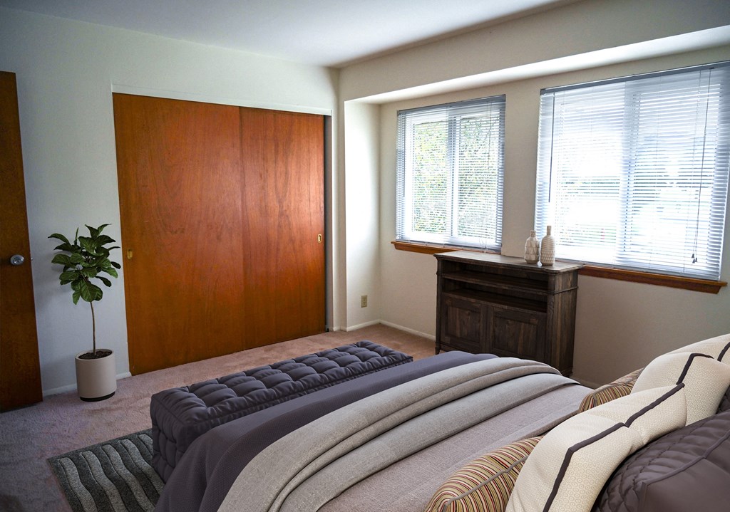 a bedroom with a bed and a dresser and two windows