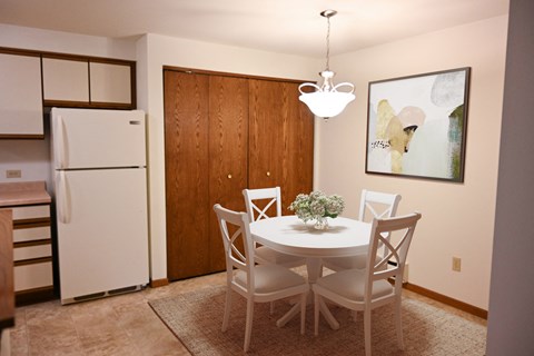 a dining room with a white table and chairs and a refrigerator