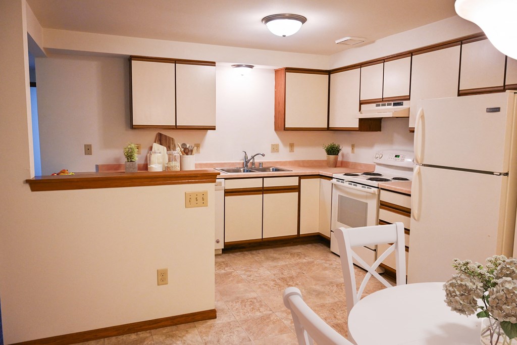a kitchen with white appliances and a table and chairs