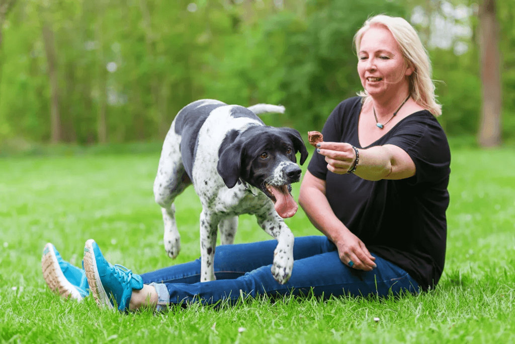 a woman sitting on the grass with her dog