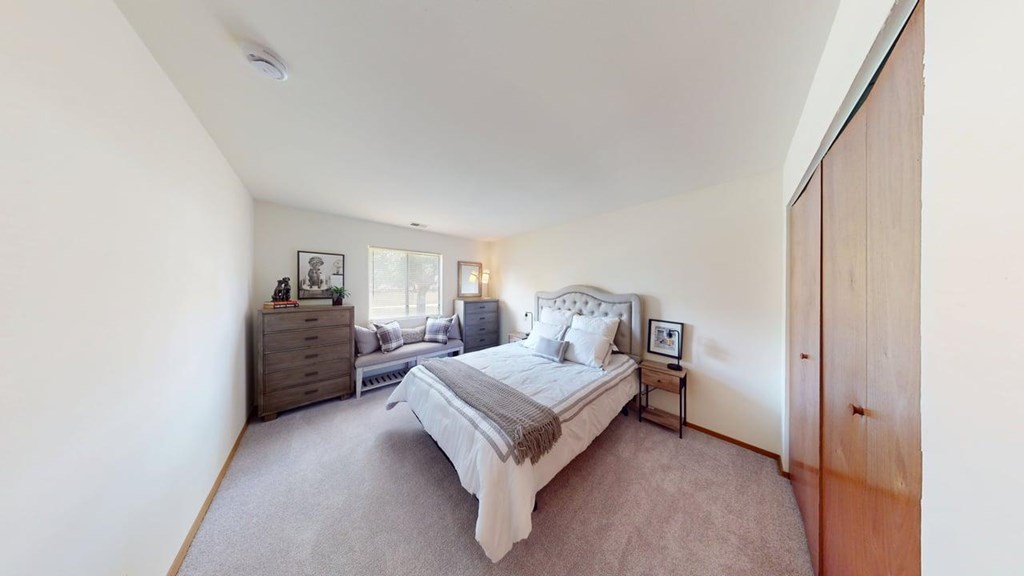 A bedroom with a large bed, a dresser, and a nightstand.