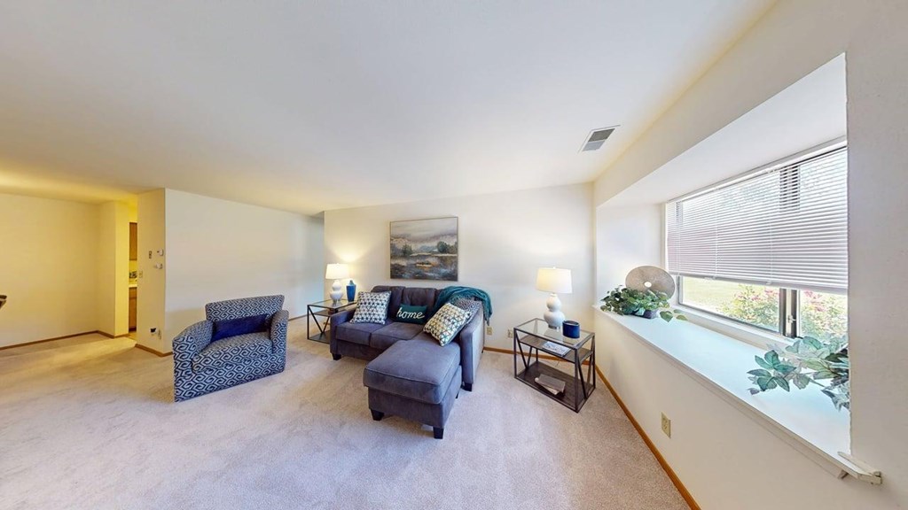 A living room with a grey sofa, a blue armchair, and a wooden cabinet.